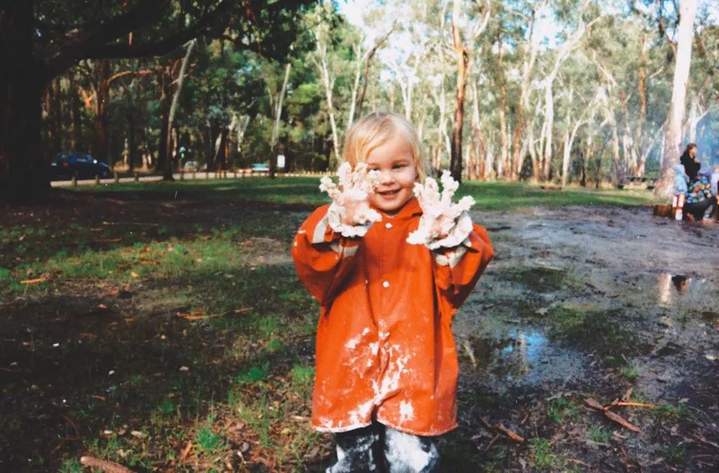 Preschool child exploring in a muddy outdoor setting